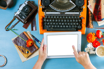 Typewriters to tablets - an old fashioned mechanical typewriter and new tablet on a desk together.